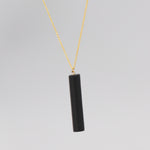 Gold necklace with a black bar pendant
